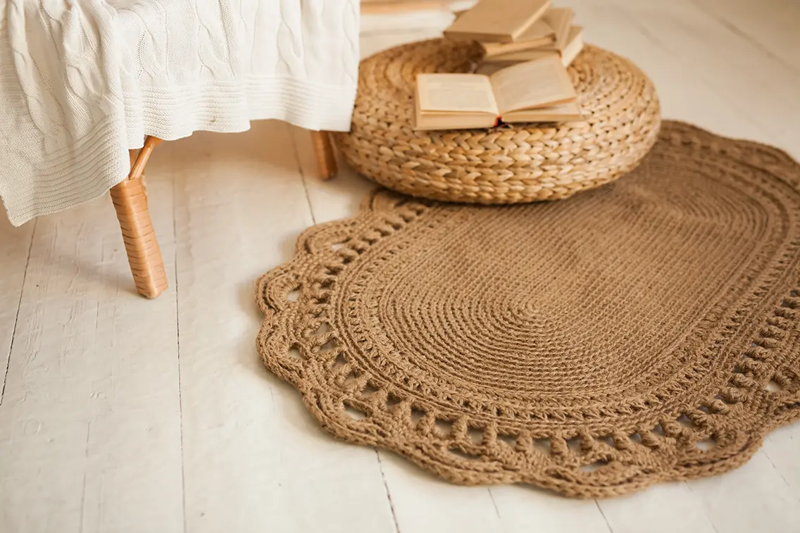 Jute rug and jute decor spread on the floor. Above the rug there is a book. The whole setup radiates a bohemian theme at home. 