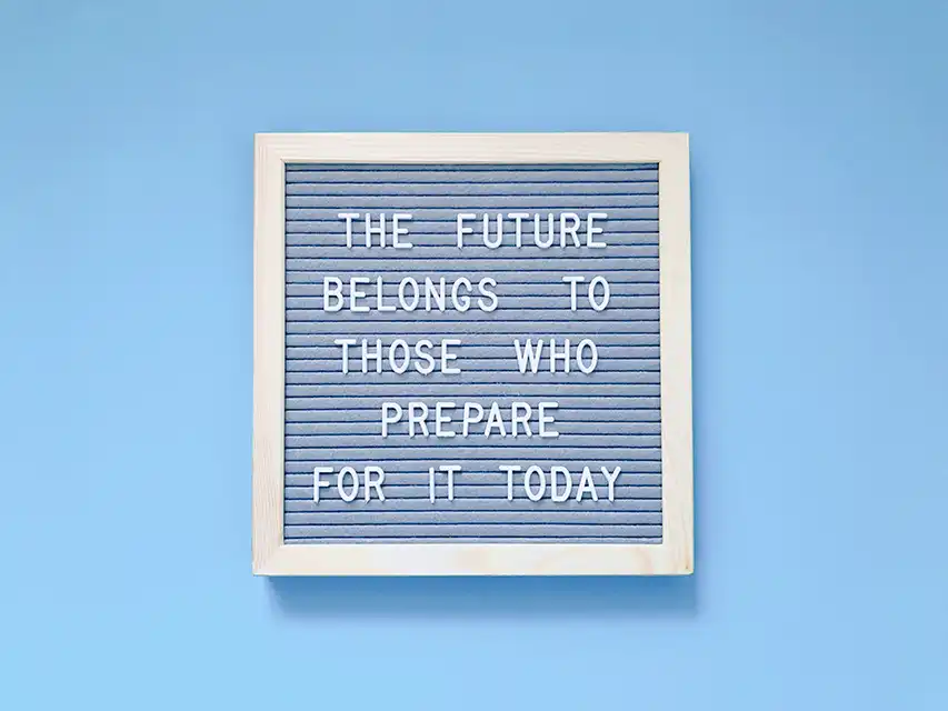 Framed letter board with motivational quote: 'THE FUTURE BELONGS TO THOSE WHO PREPARE FOR IT TODAY.' Light wooden frame, blue background, white letters.