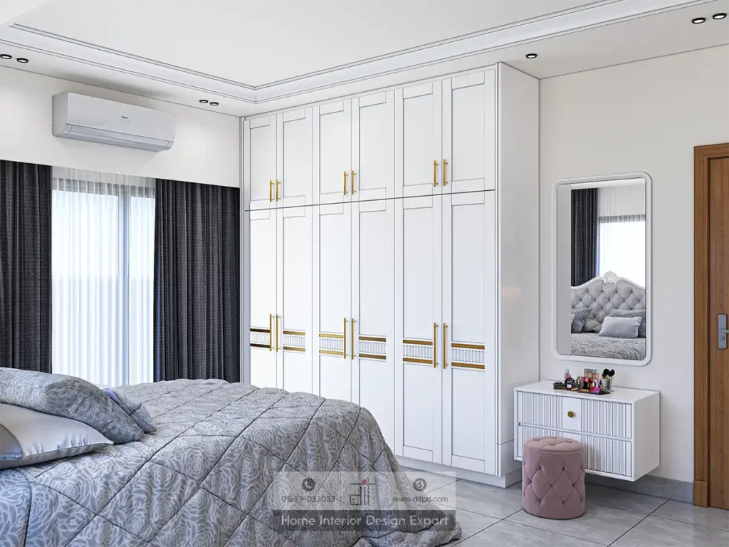 Modern bedroom with white wardrobe and gold handles, grey bedding, dark curtains, wall-mounted air conditioner, and a compact vanity setup with mirror and stool.